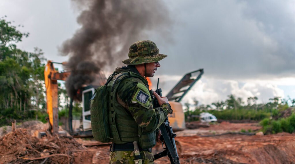 Environmental enforcement officer beside machinery in a cleared forest area